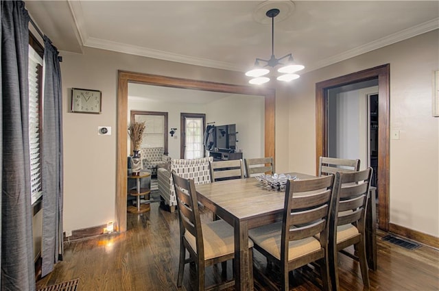 dining space with crown molding, dark hardwood / wood-style floors, and an inviting chandelier