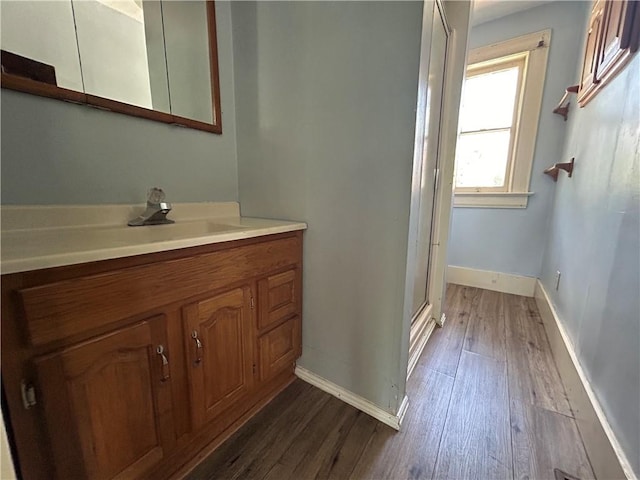 bathroom with wood-type flooring, vanity, and an enclosed shower