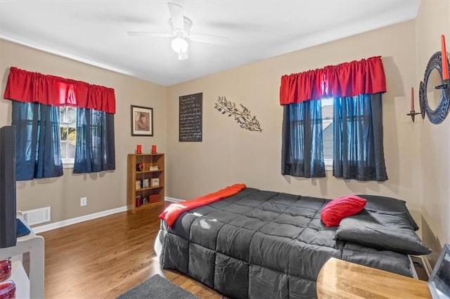 bedroom with dark hardwood / wood-style flooring, multiple windows, and ceiling fan