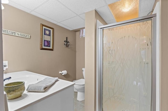 bathroom with walk in shower, toilet, a drop ceiling, and sink