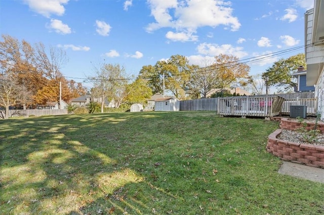 view of yard with a deck, cooling unit, and a storage shed