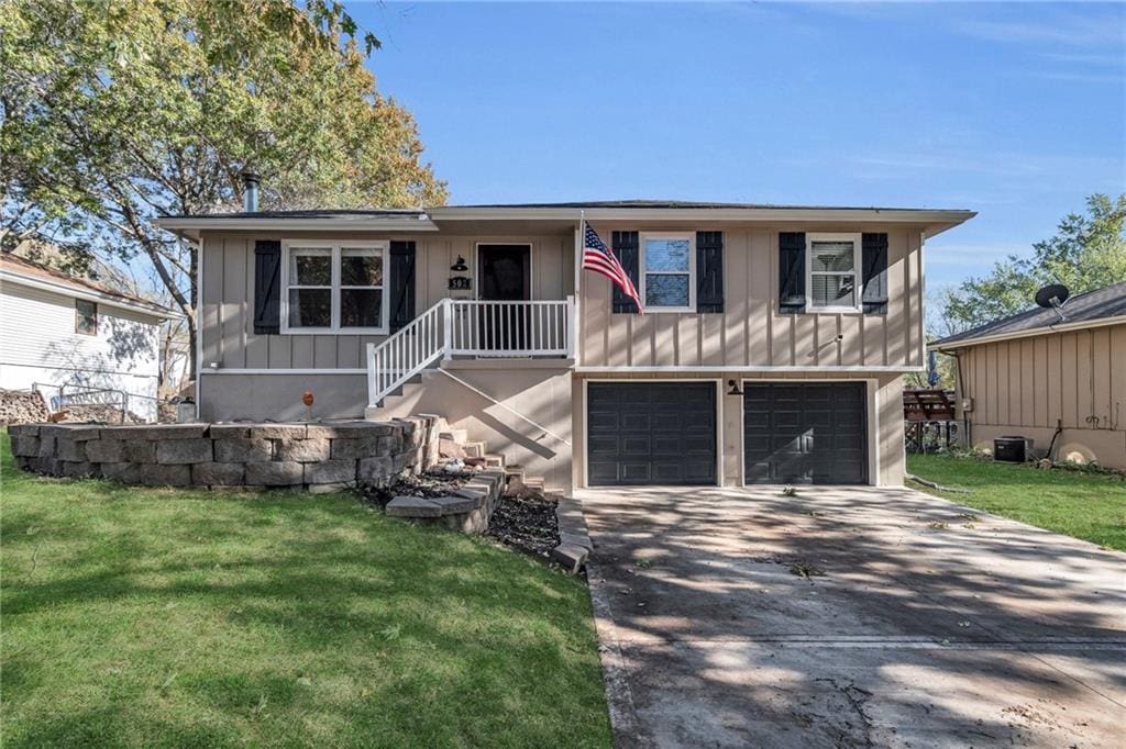 view of front of home featuring a front yard, central AC, and a garage