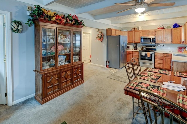 kitchen featuring stainless steel appliances, beamed ceiling, ceiling fan, wood ceiling, and light colored carpet