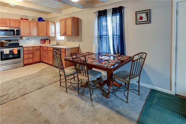 kitchen featuring wooden ceiling, stainless steel appliances, beamed ceiling, light colored carpet, and ceiling fan