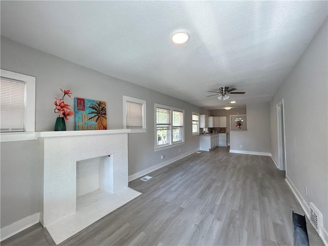 unfurnished living room with a textured ceiling, a fireplace, hardwood / wood-style flooring, and ceiling fan