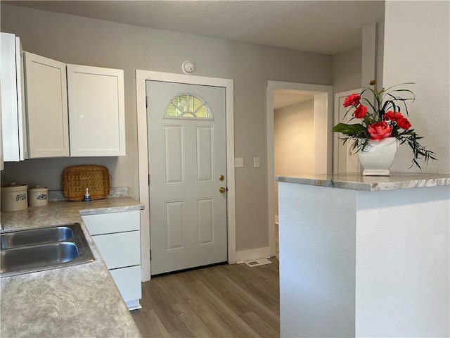 kitchen featuring white cabinets, sink, and light wood-type flooring