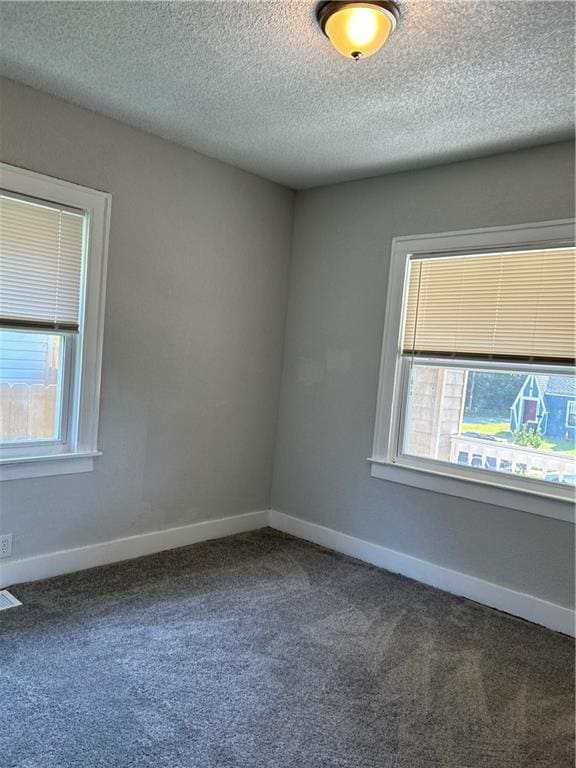 unfurnished room with a textured ceiling and dark carpet