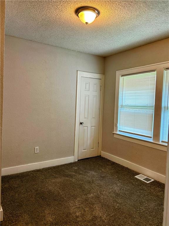 empty room featuring dark colored carpet and a textured ceiling