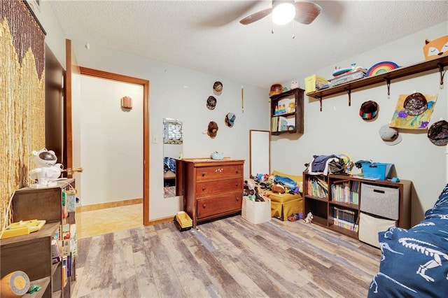 interior space featuring ceiling fan, light wood-type flooring, and a textured ceiling