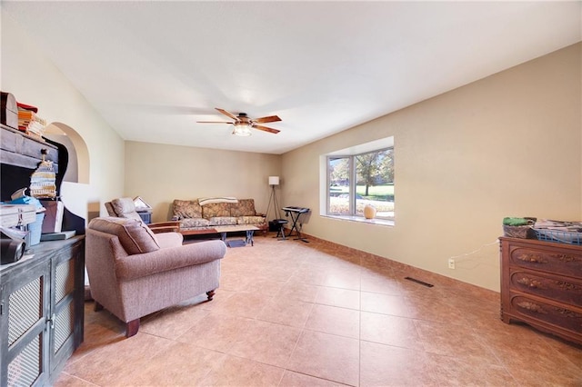 tiled living room featuring ceiling fan and a fireplace