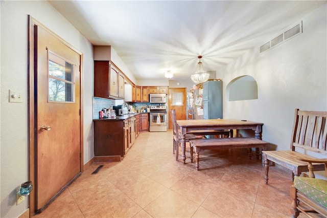 tiled dining room with an inviting chandelier