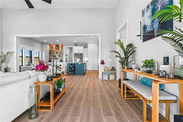 living room featuring hardwood / wood-style flooring, ceiling fan, and a high ceiling