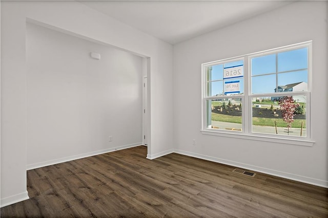 spare room with dark hardwood / wood-style flooring and a healthy amount of sunlight