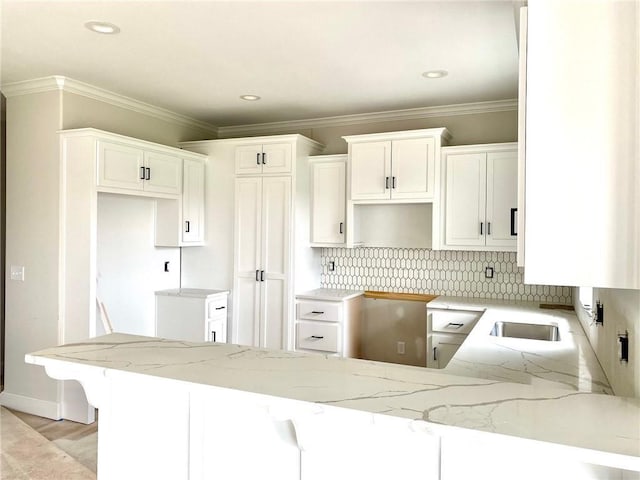 kitchen with light stone countertops, tasteful backsplash, a peninsula, and ornamental molding