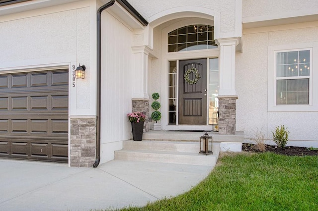 property entrance featuring a garage, stone siding, and stucco siding