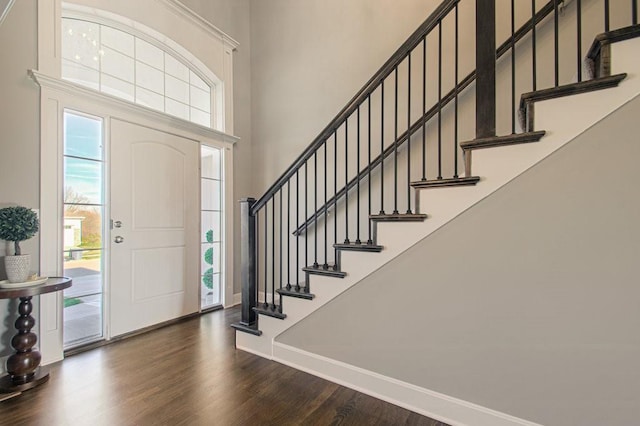 entrance foyer with dark wood finished floors, stairs, baseboards, and a towering ceiling