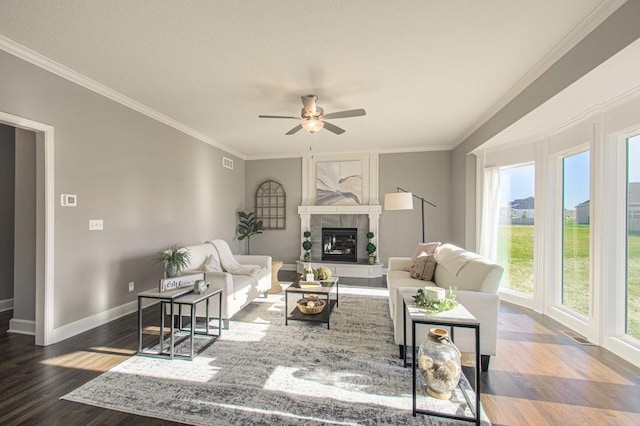 living room with a glass covered fireplace, crown molding, baseboards, and wood finished floors