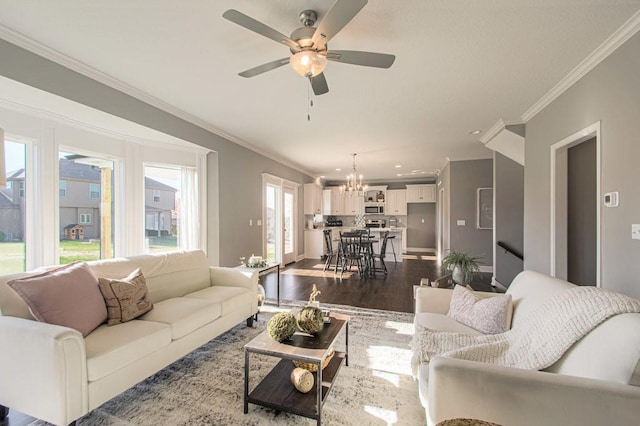 living room with ceiling fan with notable chandelier, wood finished floors, baseboards, and ornamental molding