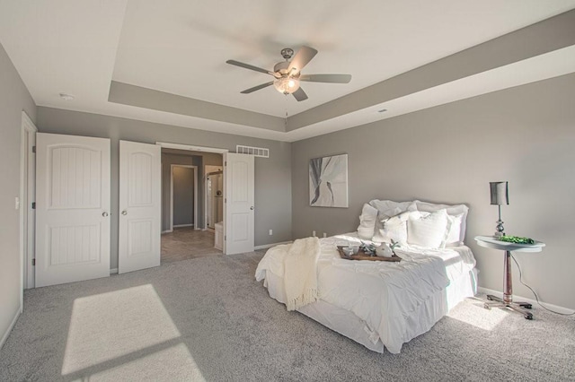 bedroom with visible vents, a raised ceiling, baseboards, and carpet flooring