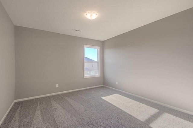 carpeted spare room featuring visible vents and baseboards