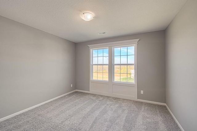 spare room featuring baseboards, visible vents, carpet floors, and a textured ceiling