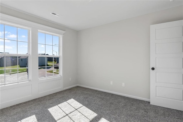 empty room with visible vents, baseboards, and carpet flooring