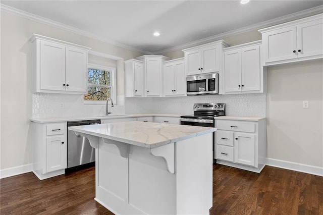 kitchen with tasteful backsplash, a kitchen island, stainless steel appliances, white cabinetry, and a sink