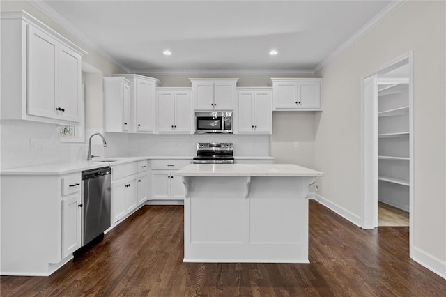 kitchen with a sink, decorative backsplash, appliances with stainless steel finishes, white cabinetry, and crown molding