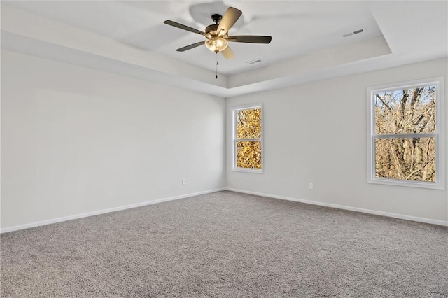 unfurnished room with a tray ceiling, baseboards, and carpet floors