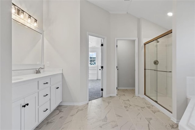 bathroom with baseboards, lofted ceiling, marble finish floor, and a shower stall