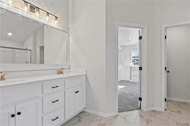 full bath featuring double vanity, marble finish floor, a shower stall, and a sink