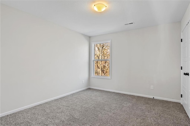 carpeted spare room featuring visible vents and baseboards