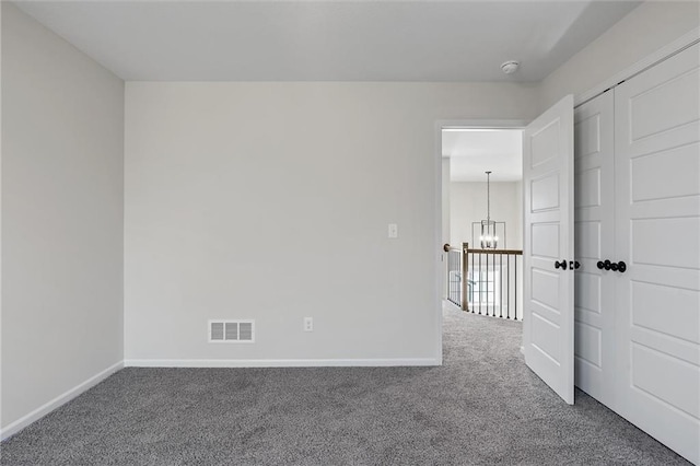 empty room featuring visible vents, baseboards, carpet, and a notable chandelier