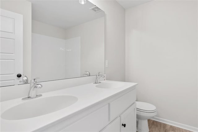 bathroom with toilet, wood finished floors, visible vents, and a sink