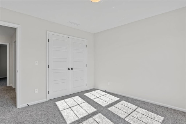 unfurnished bedroom with a closet, visible vents, baseboards, and carpet