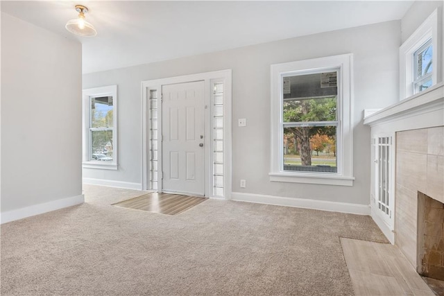 carpeted entryway with a tile fireplace