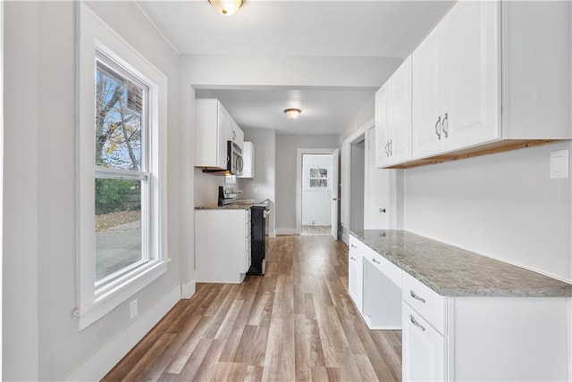 kitchen with appliances with stainless steel finishes, light wood-type flooring, and white cabinetry