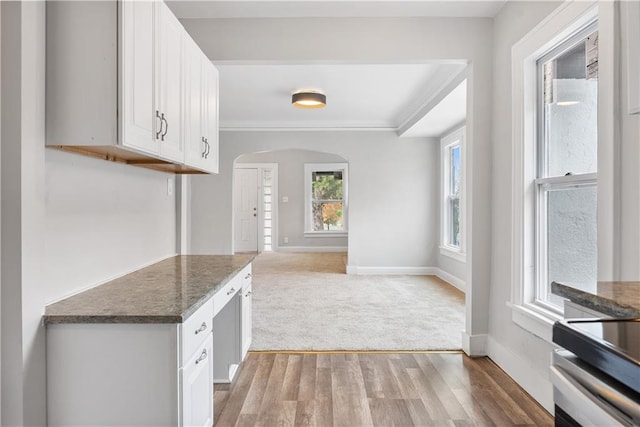 kitchen featuring dark stone countertops, white cabinetry, crown molding, and light hardwood / wood-style flooring