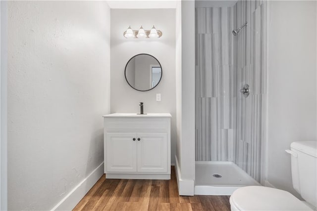 bathroom with a shower, hardwood / wood-style floors, vanity, and toilet