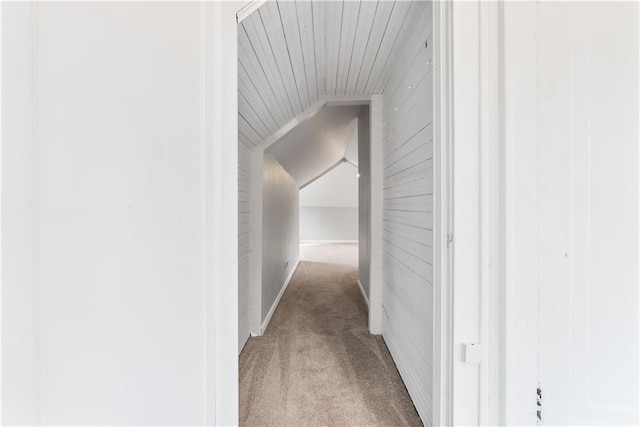 hallway featuring wood ceiling, light colored carpet, lofted ceiling, and wooden walls