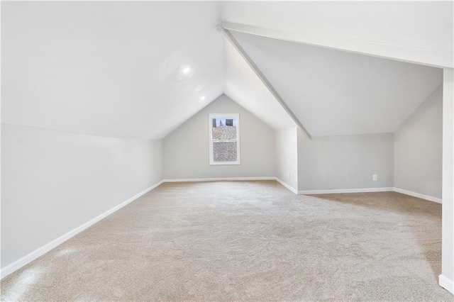 additional living space featuring light colored carpet and vaulted ceiling