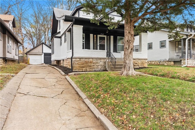 view of front of home featuring a front yard, a porch, a garage, and an outdoor structure