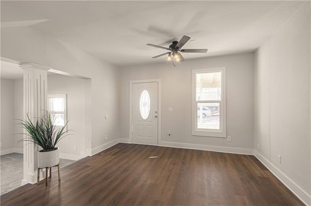 entrance foyer with ceiling fan, ornate columns, and dark wood-type flooring