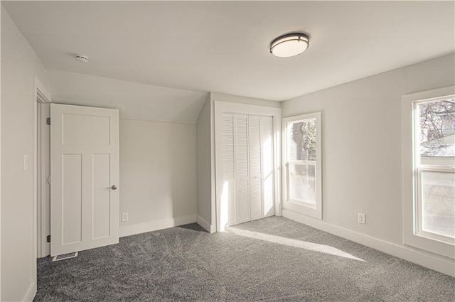 unfurnished bedroom featuring a closet, dark carpet, and vaulted ceiling