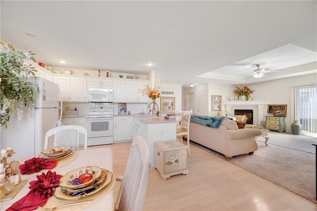 kitchen featuring ceiling fan, a center island, light hardwood / wood-style flooring, white appliances, and white cabinets