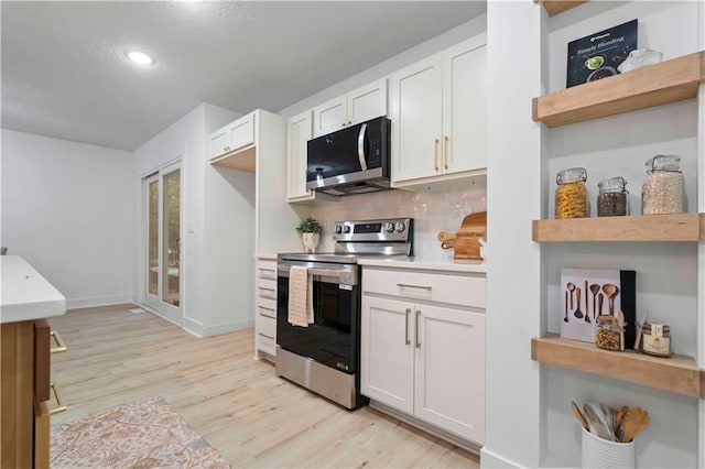 kitchen with white cabinetry, backsplash, appliances with stainless steel finishes, and light hardwood / wood-style floors