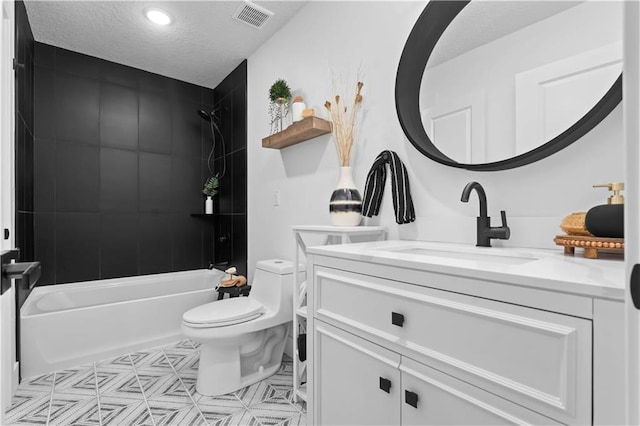 full bathroom with vanity, a textured ceiling, tiled shower / bath combo, and toilet