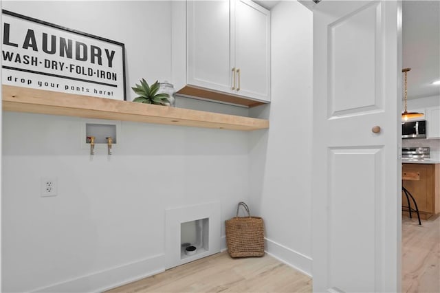 clothes washing area with electric dryer hookup, cabinets, light hardwood / wood-style floors, and hookup for a washing machine