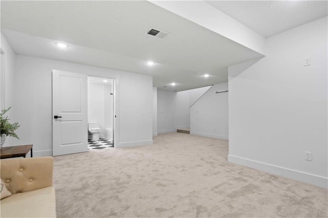 finished below grade area with visible vents, baseboards, stairs, light carpet, and recessed lighting