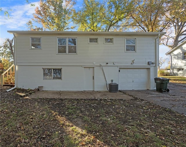 back of property featuring a garage and central AC unit